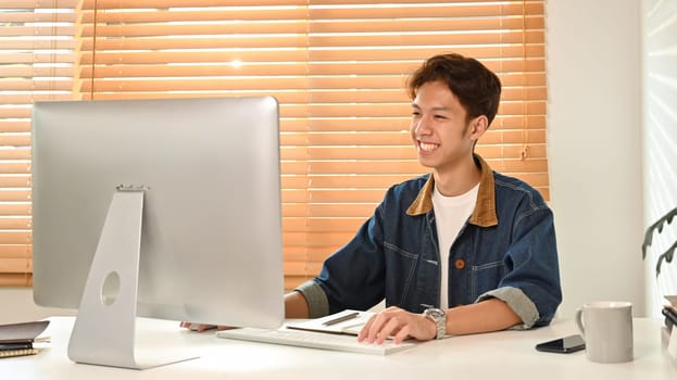 Image of asian male in smart casual wears using laptop at home office. Freelance, distance, education, e-learning concept.