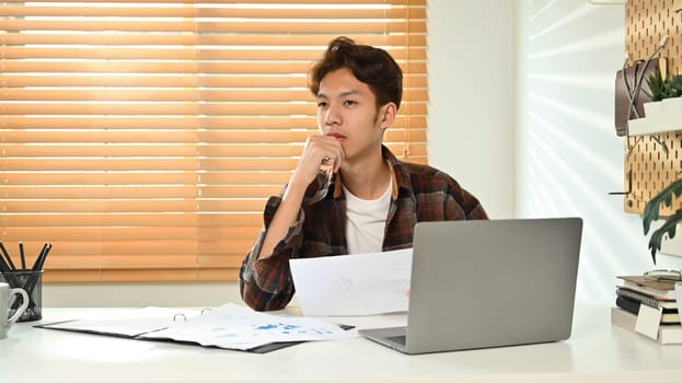 Image of asian male in smart casual wears using laptop at home office. Freelance, distance, education, e-learning concept.