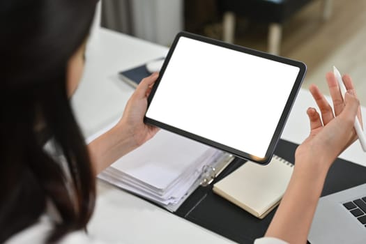 View over shoulder of businesswoman hands holding digital tablet. White screen for graphic display montage.