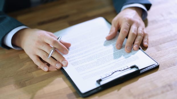 Businessman with pen in hands studying contract at table in office closeup. Profitable business deal concept