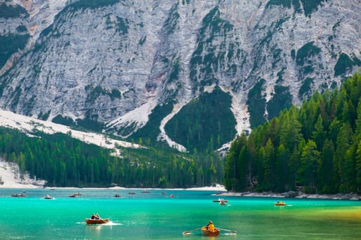 Stunning view of Lake Braies or Lago di Braies with tourists riding wooden boats. Entertainment on the lake on the alpine lake.