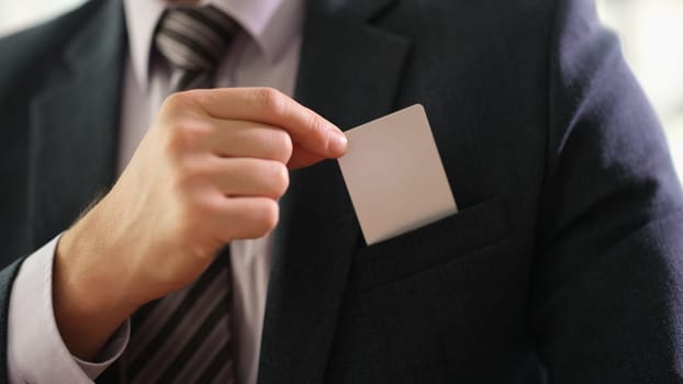 Businessman in suit and tie taking out business card from pocket of jacket closeup. Contact id information concept