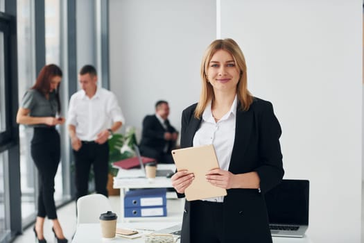 Woman in front of her colleagues. Group of people in official formal clothes that is indoors in the office.