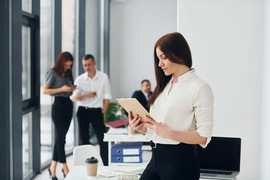 Woman in front of her colleagues. Group of people in official formal clothes that is indoors in the office.