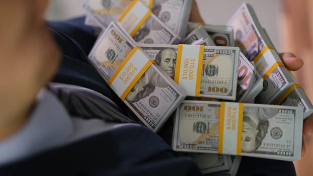 Businessman holding many packs of dollar bills closeup. Successful business financial growth concept