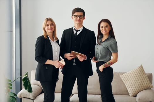 Young guy and two women in formal official clothes together indoors.