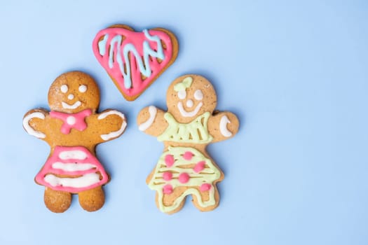 Black and white homosexual couple, two gingerbread girls and heart on the blue background with copy space for St Valentines Day.