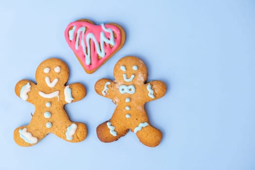 Black and white homosexual couple, two gingerbread girls and heart on the blue background with copy space for St Valentines Day.