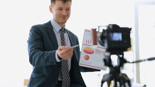 Businessman coach showing documents with graphs to camera. Freelance and business education concept