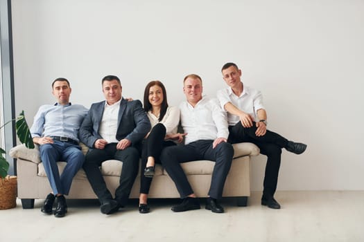 Group of office workers in formal official clothes is together indoors.