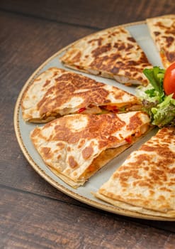 Mexican quesadilla with chicken, cheese and peppers on wooden table