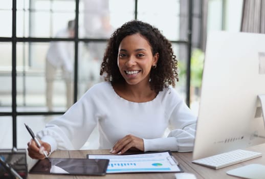 woman sitting at desktop with laptop noting down important information