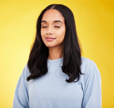 Indian woman with eyes closed, meditation and zen with peace and calm isolated on yellow studio background. Mental health, wellness and balance with stress relief, young female relax with mindfulness.