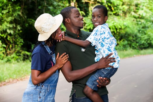 a family standing in a park watching their son smiling.