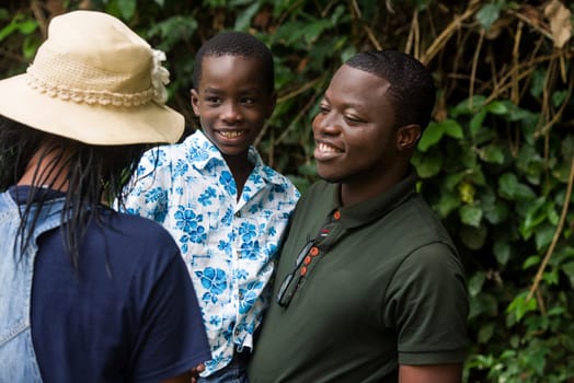 a family standing near a bush looking at each other with a smile.