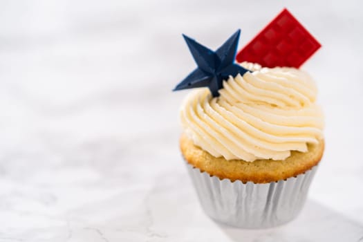 Lemon cupcakes with lemon buttercream frosting, and decorated with patriotic blue chocolate star and red mini chocolate.