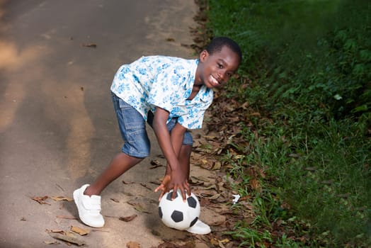 a young boy playing a ball in a park laughing.