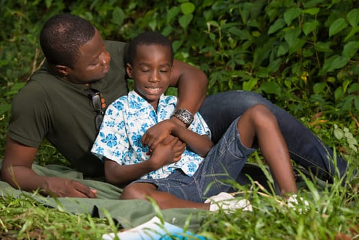 a young man lying in a park watching his son smiling.
