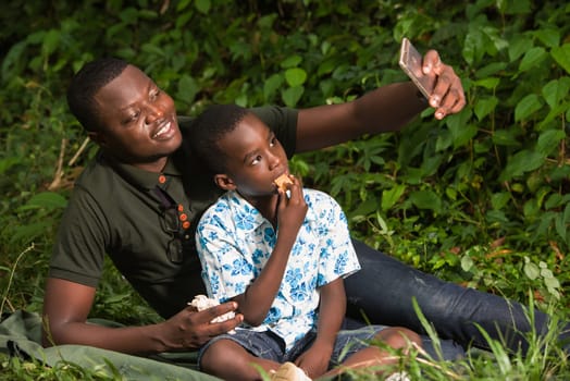 a young family in a park watching mobile phone while smiling.