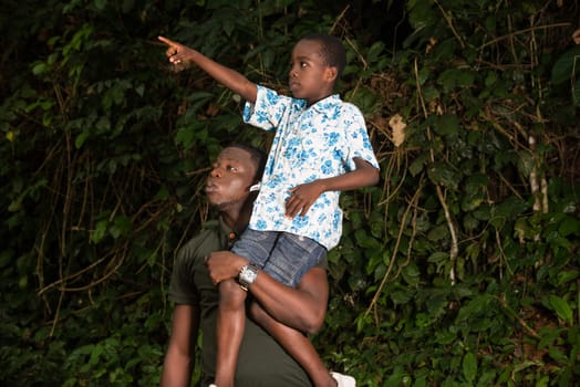 a young boy on the shoulder of his father showing him something up there.