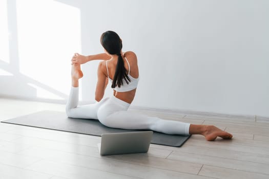 With laptop. Young caucasian woman with slim body shape is indoors at daytime.