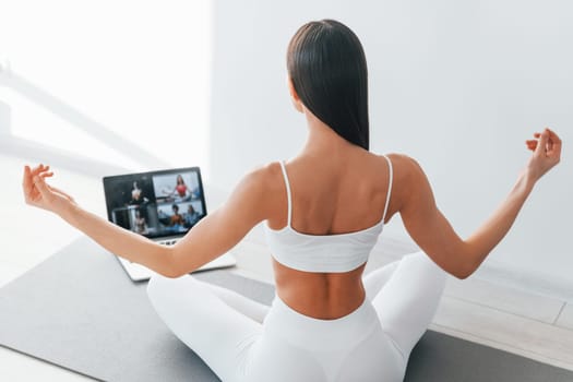 With laptop. Young caucasian woman with slim body shape is indoors at daytime.