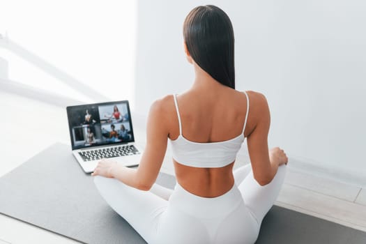 With laptop. Young caucasian woman with slim body shape is indoors at daytime.