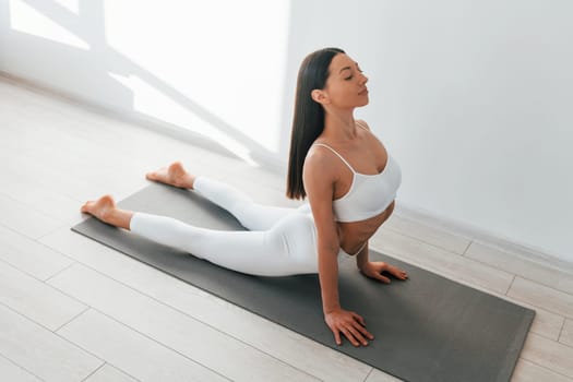 Doing exercises. Young caucasian woman with slim body shape is indoors at daytime.