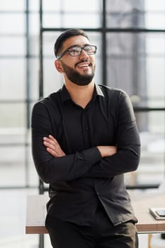 young businessman smiling in the office with his arms crossed