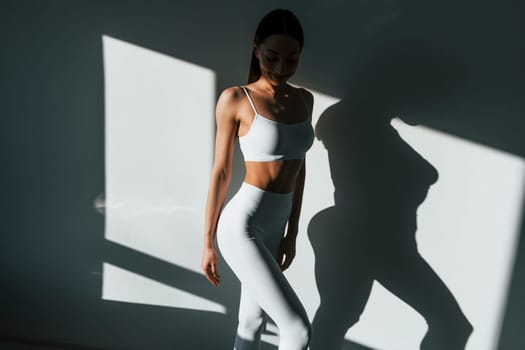 Beautiful lighting. Young caucasian woman with slim body shape is indoors at daytime.
