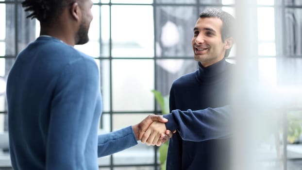 Diverse male colleagues in modern office corridor, young african american and caucasian business people discussing common project work, meeting in company work