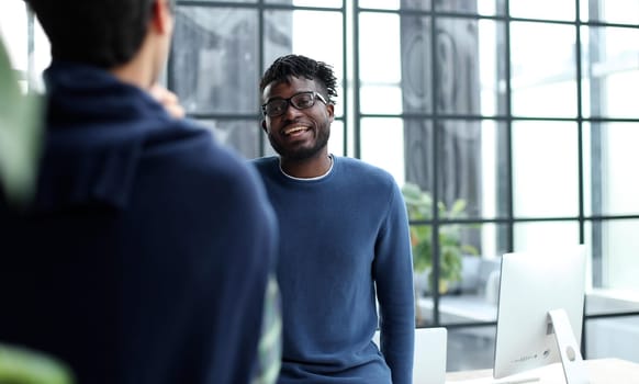 Diverse male colleagues in modern office corridor, young african american and caucasian business people discussing common project work, meeting in company work