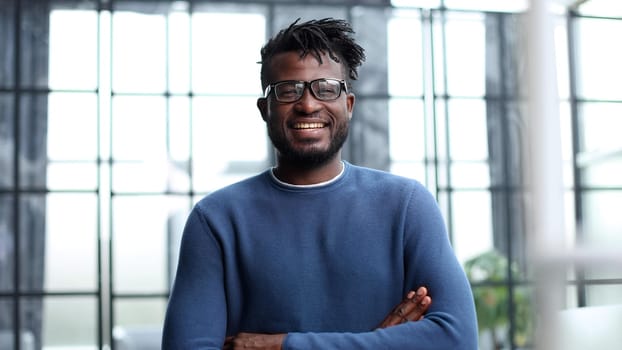 Portrait of a happy confident young african american businessman standing with his arms crossed looking at camera