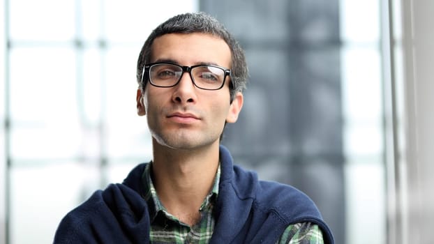 man wearing glasses looking at camera with a serious expression in a close up head and shoulders portrait