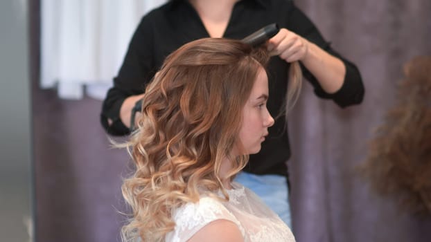 Girl hairdresser doing hairstyle in the form of spinning hair