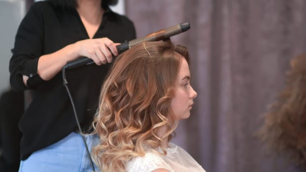 Girl hairdresser doing hairstyle in the form of spinning hair