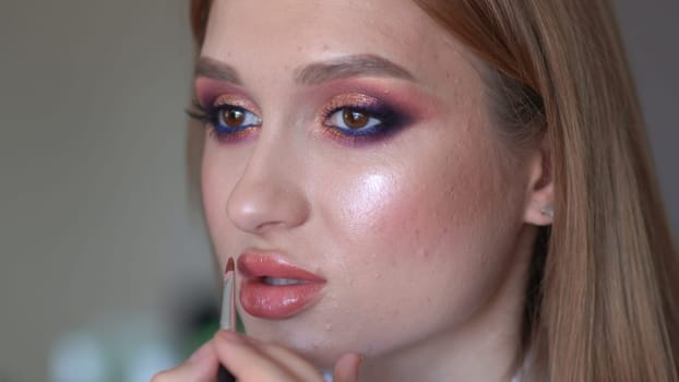 Makeup artist paints lips of a model girl
