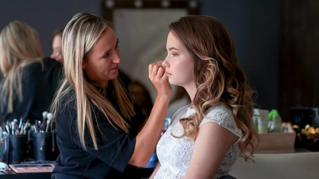 Makeup artist paints the eyes of a girl model.