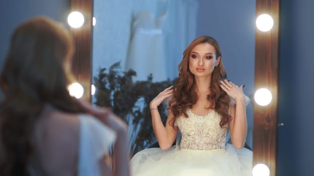 Beautiful girl model in wedding dress posing in front of a mirror