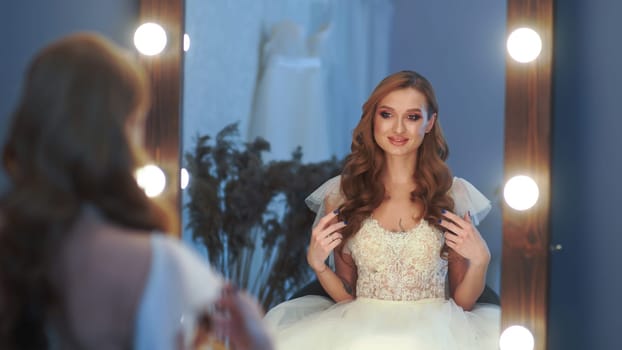 Beautiful girl model in wedding dress posing in front of a mirror