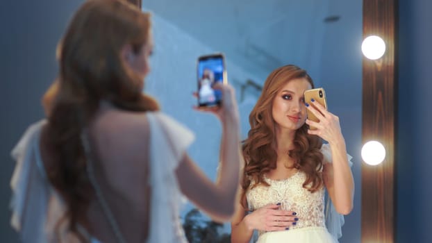 Beautiful girl model posing in front of a mirror and taking pictures on a smartphone