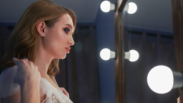 After applying makeup, the girl poses in front of the mirror