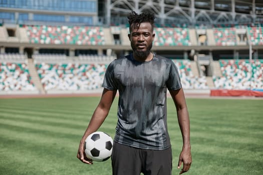Intense portrait of a football player holding the ball in the stadium