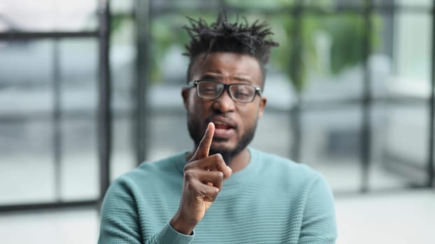 Portrait of a serious african american man, shaking his finger, warning and preventing you from something bad, looking at the camera with a worried expression.