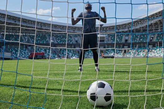 African American soccer player kicking ball inside large stadium