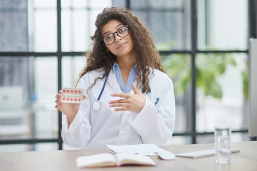 Portrait of young female doctor in white coat at workplace