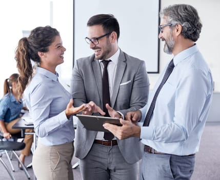 A portrait of a young and senior smiling businesspeople holding a tablet during a meeting and presentation in the office. Business concept