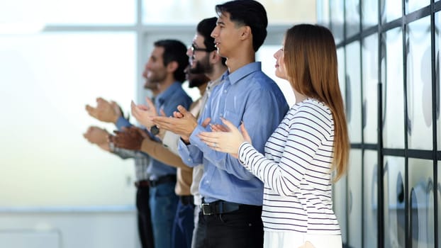 Applause. Group of cheerful young multi-ethnic people standing in a row and applauding to someone while standing