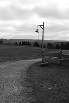 Grayscale of an old lantern with a wooden pole in front of Steinberg Alm in Harz Mountains, Germany