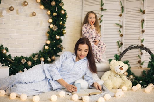 happy mother with her little child daughter playing near the Christmas tree